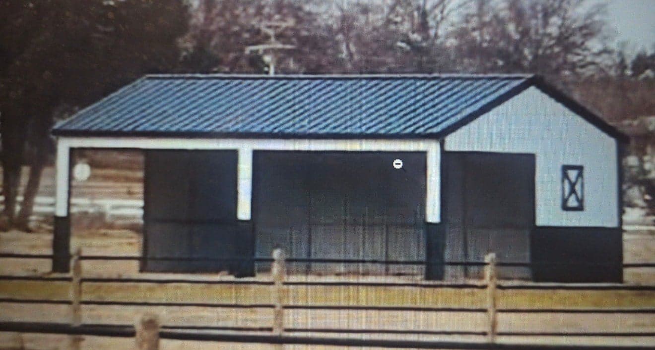 Premium estate loafing shed — black panels, white trim, open frameout bays, kick panels, board fence